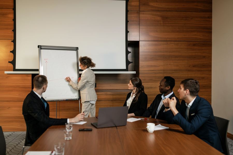 Advisor presenting strategy on a whiteboard to a seated team