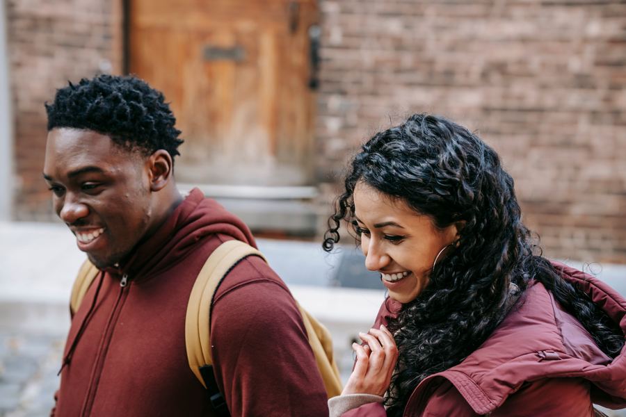 Two students walking and smiling on campus